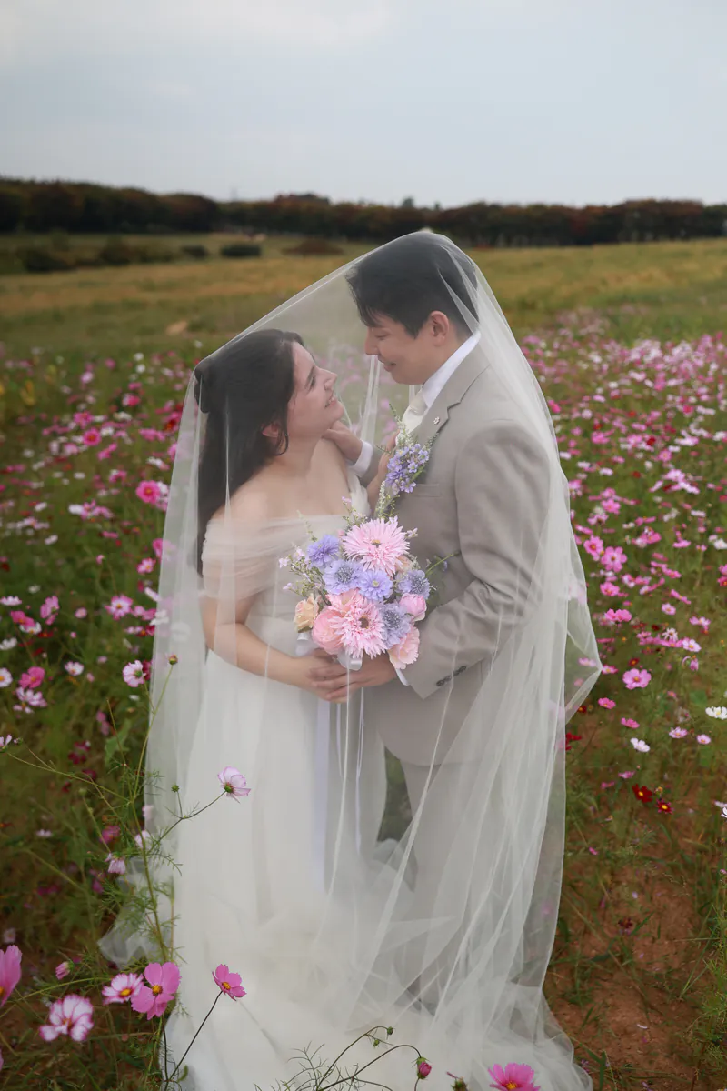 Sara e Jiwon baixo un veo nun campo de cosmos