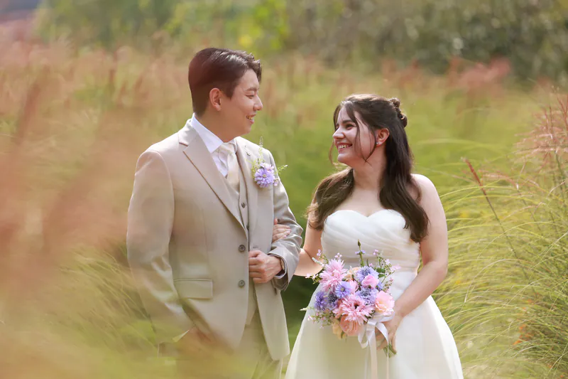 Sara e Jiwon sorrindo entre herba alta de outono