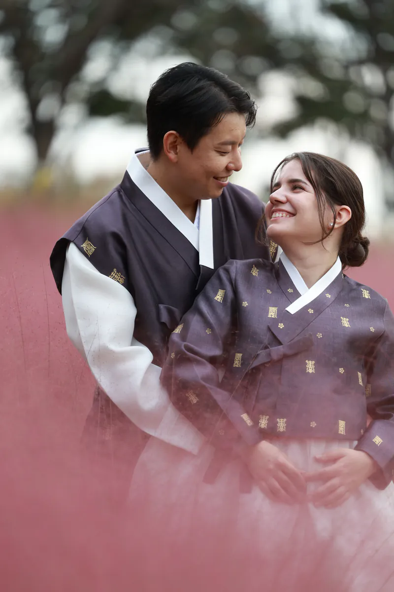 Jiwon abrazando a Sara, con hanbok, diante de herba rosa